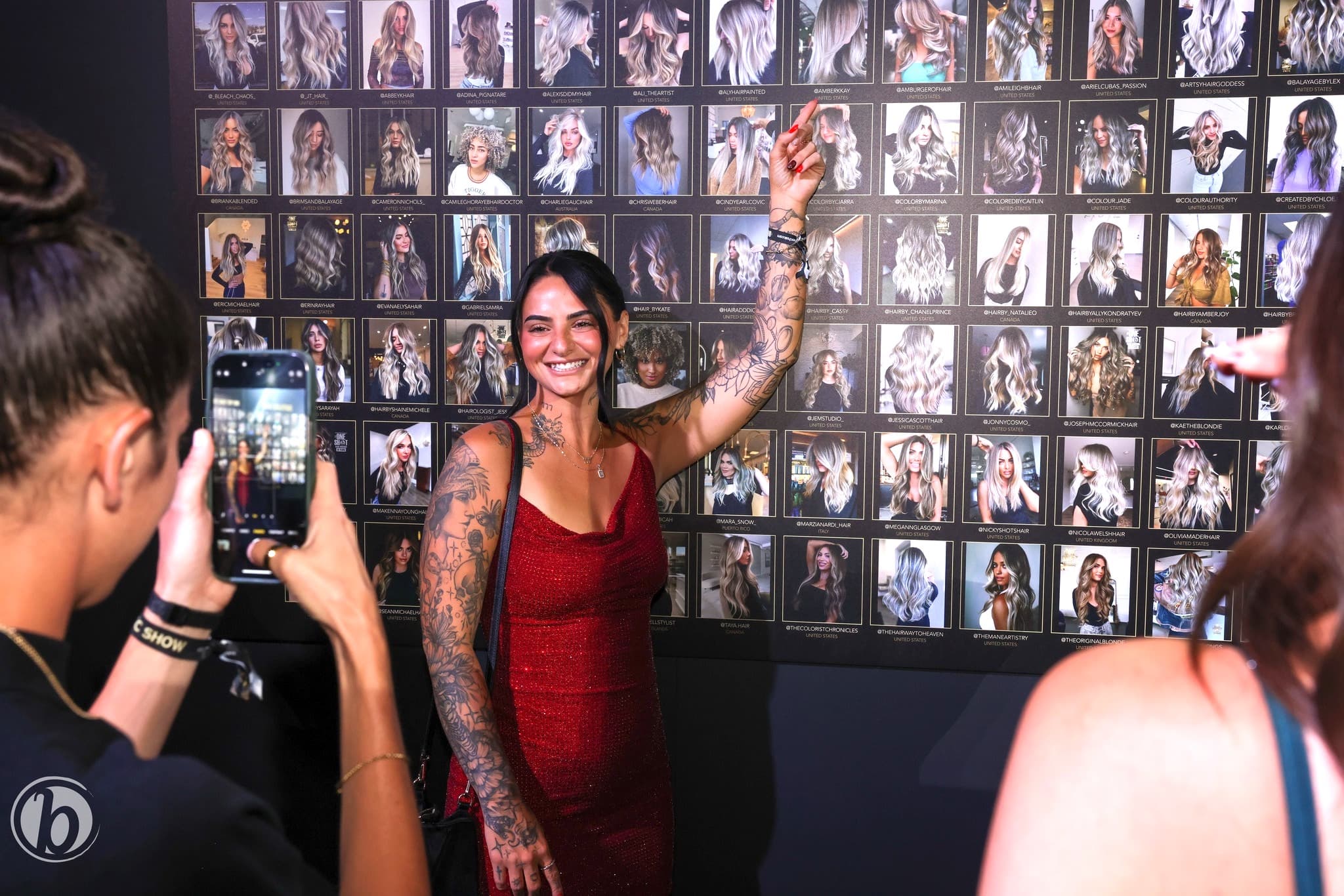 #ONESHOT nominee posing in front of the gallery wall of finalist photos